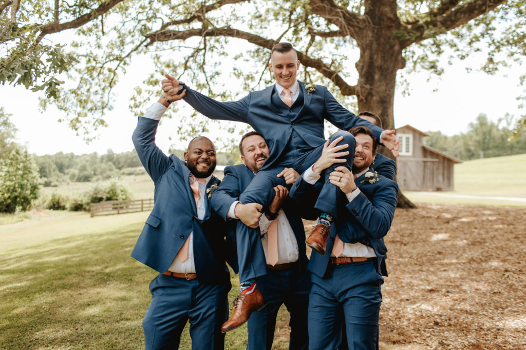 groom and groomsmen throwing groom up in the air