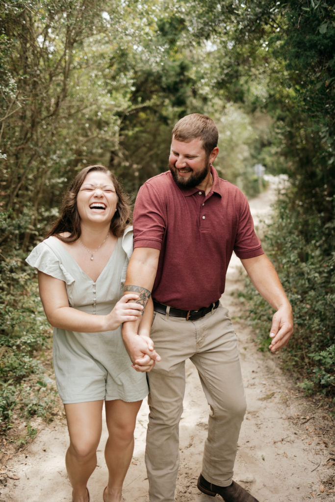 Couple walking and laughing at Jekyll Island Driftwood Beach engagement session