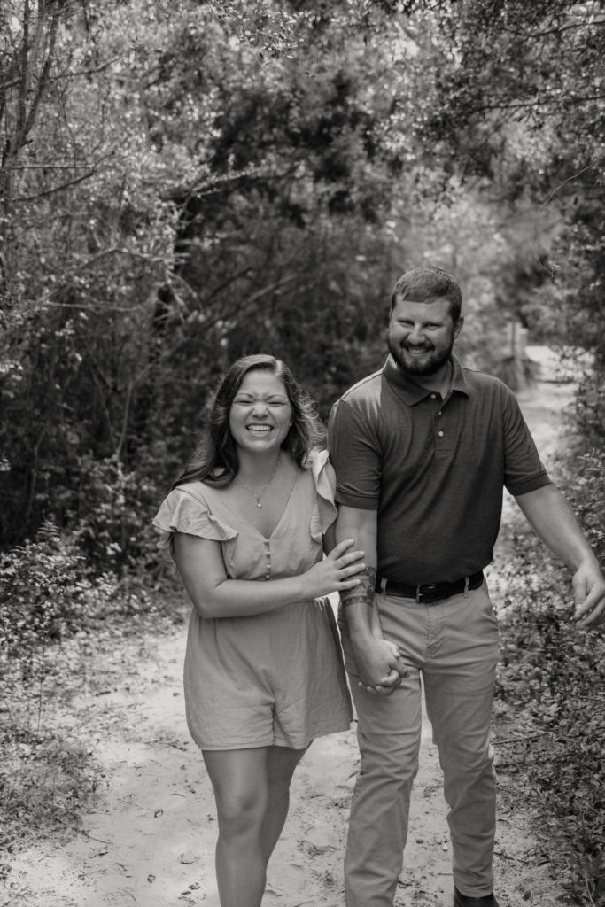 Newly engaged couple laughing at Jekyll Island Driftwood Beach engagement session