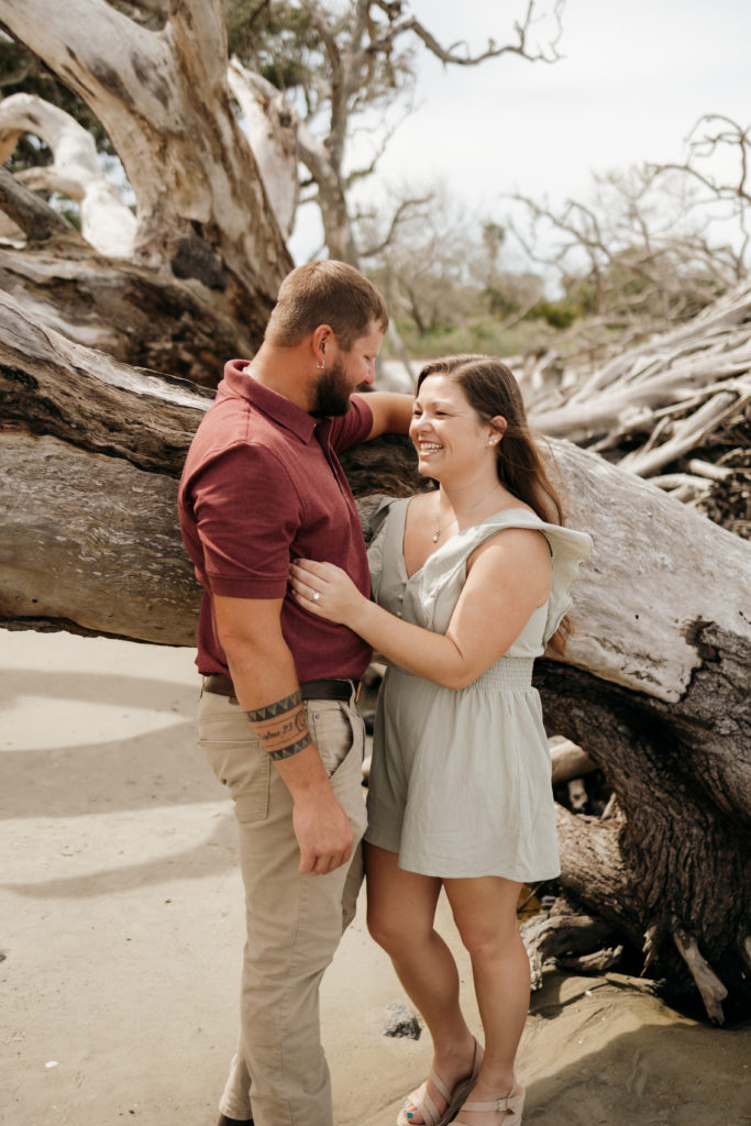 Couple posing in front of driftwood at Jekyll Island Driftwood Beach engagement session