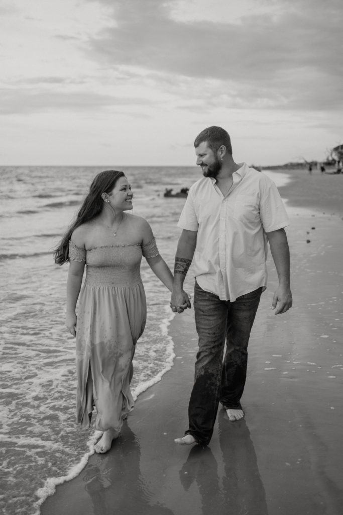 Newly engaged walking the beach at Jekyll Island Driftwood Beach engagement session
