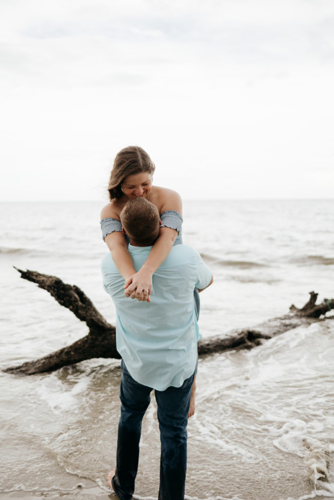 Man holding woman during beach engagement session